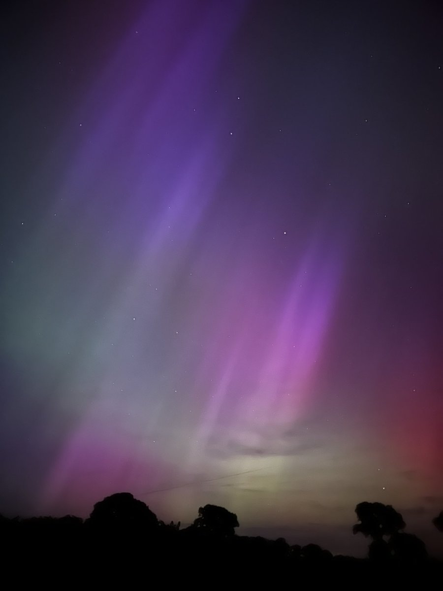 On arrival they cause the gas in atmosphere to glow like a neon tube. The different gasses give the different colours; green is low altitude oxygen, red is high altitude oxygen, other colours are nitrogen