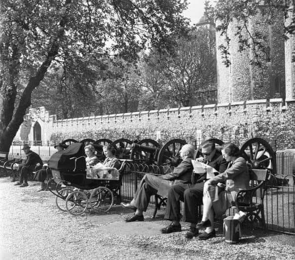 A photograph of Londoners enjoying some late spring/early summer sun on the north bank of the river Thames outside the Tower of London, taken in 1955.