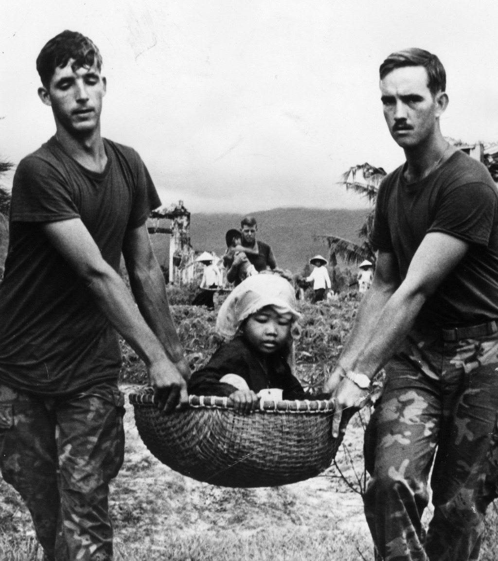 Two allied Marines carrying a young Vietnamese refugee in a basket during the evacuation of a village near Da Nang, July 1970.

Source: War History Online
 #MilitaryHistory #WarHistory