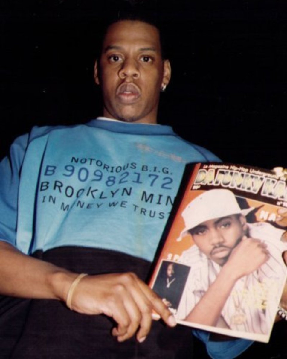 Jay-Z wearing a Biggie t-shirt, holding a magazine featuring Nas and Tupac. 🥩🐄