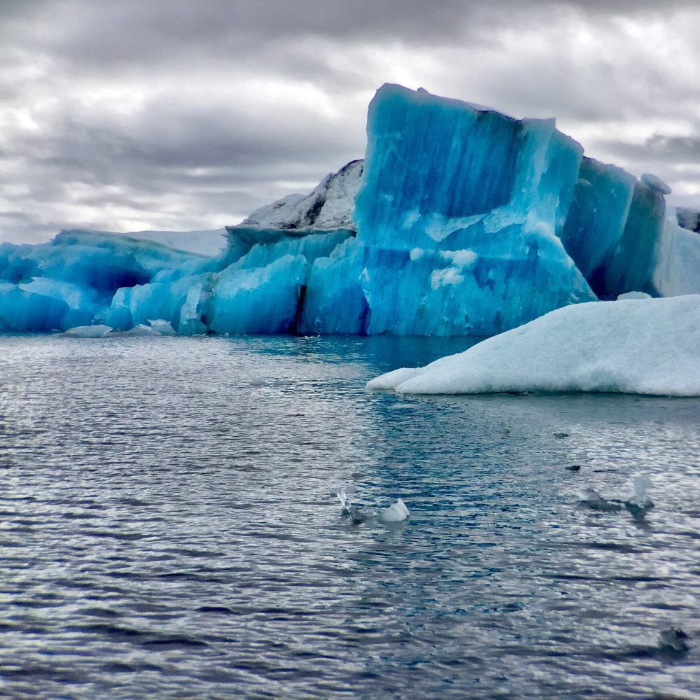 H54355Know's tweet photo. A stunning blue iceberg is a natural phenomenon where the ice appears strikingly blue. 

The ice in these icebergs has been compressed under immense pressure, forcing out tiny air bubbles. 

Without these bubbles, the light is not scattered as much, allowing the deep blue colour to emerge.