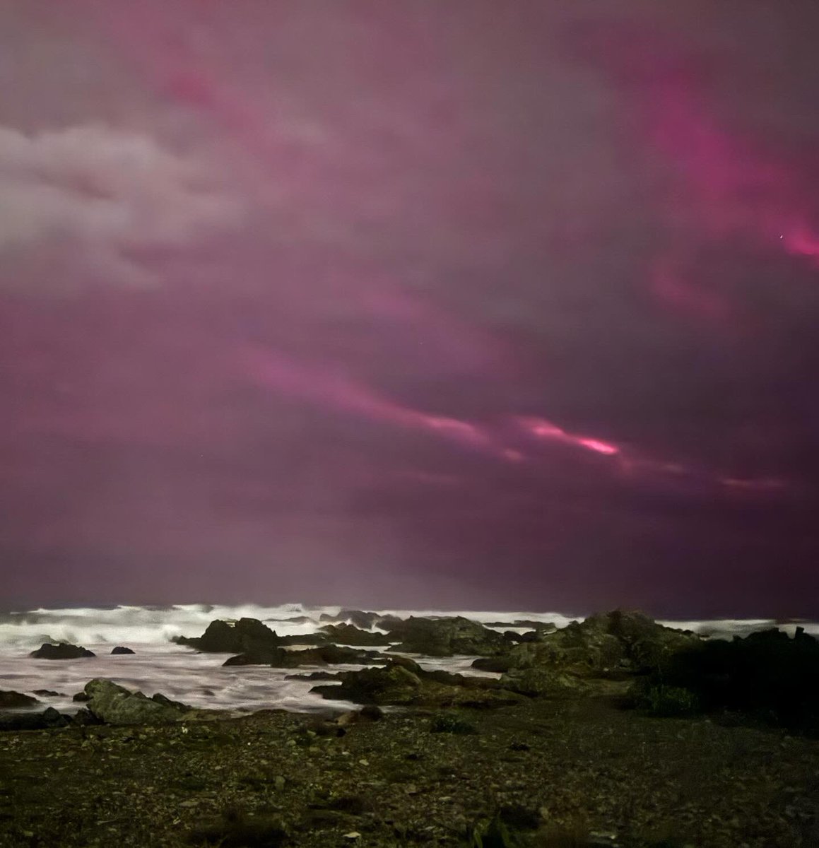 BritMumInNZ's tweet photo. It was cloudy by the time I went to look at the #auroraaustralis on Wellington’s south coast last night, but it was still beautiful to see dancing light beaming through the clouds and sea mist. The air was charged with sea spray and excitement. https://t.co/BtTKtl5P0A