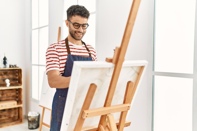 Un homme peint devant un chevalet dans un studio d’art.