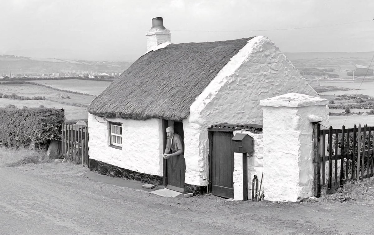 1959: Islandmagee, County Antrim Thos Jas Montgomery pictured at the front door of his wonderfully maintained one room dwelling. However, this sturdy little structure should not be confused with the notorious 'cabin' of the pre-Famine 1841 census. #vernacular #Ireland #heritage