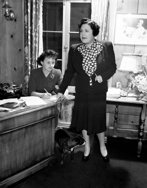 Hollywood gossip columnist Louella Parsons photographed with her secretary and her Boston Terrier, Patsy, at her Beverly Hills home in 1941.