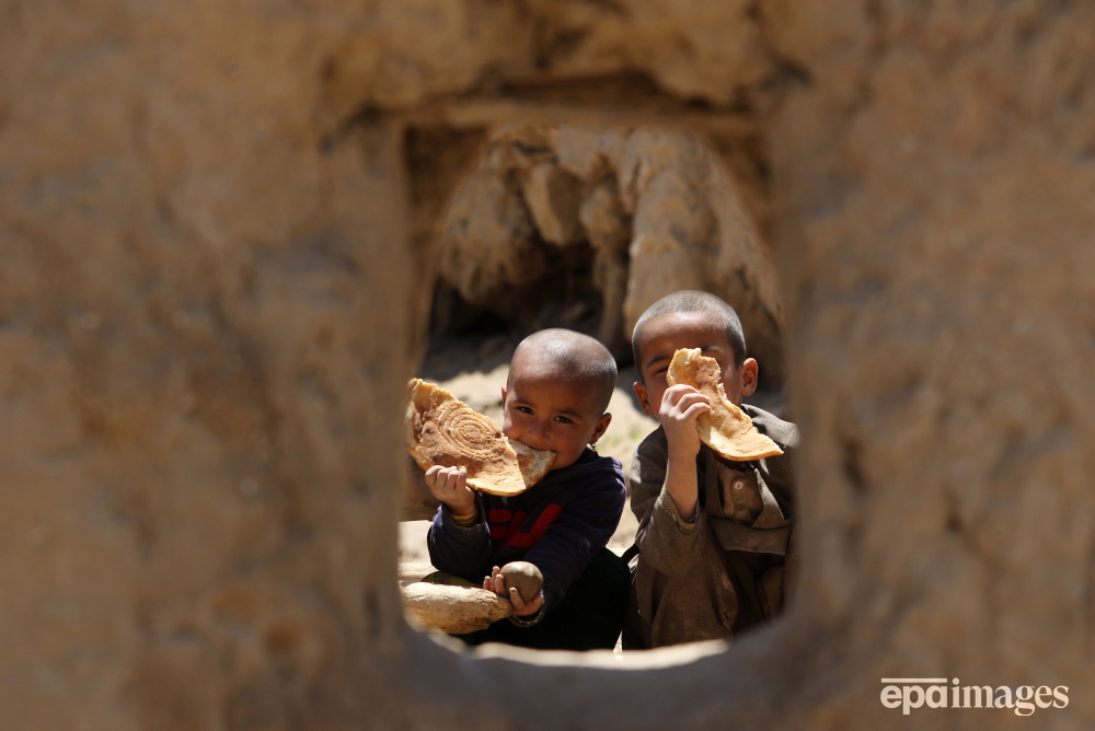 Children affected by floods eat bread that they received as aid at Shirjalal village in Baghlan, Afghanistan. 📸 EPA/Samiullah Popal #epaimages #afghanistan #flood