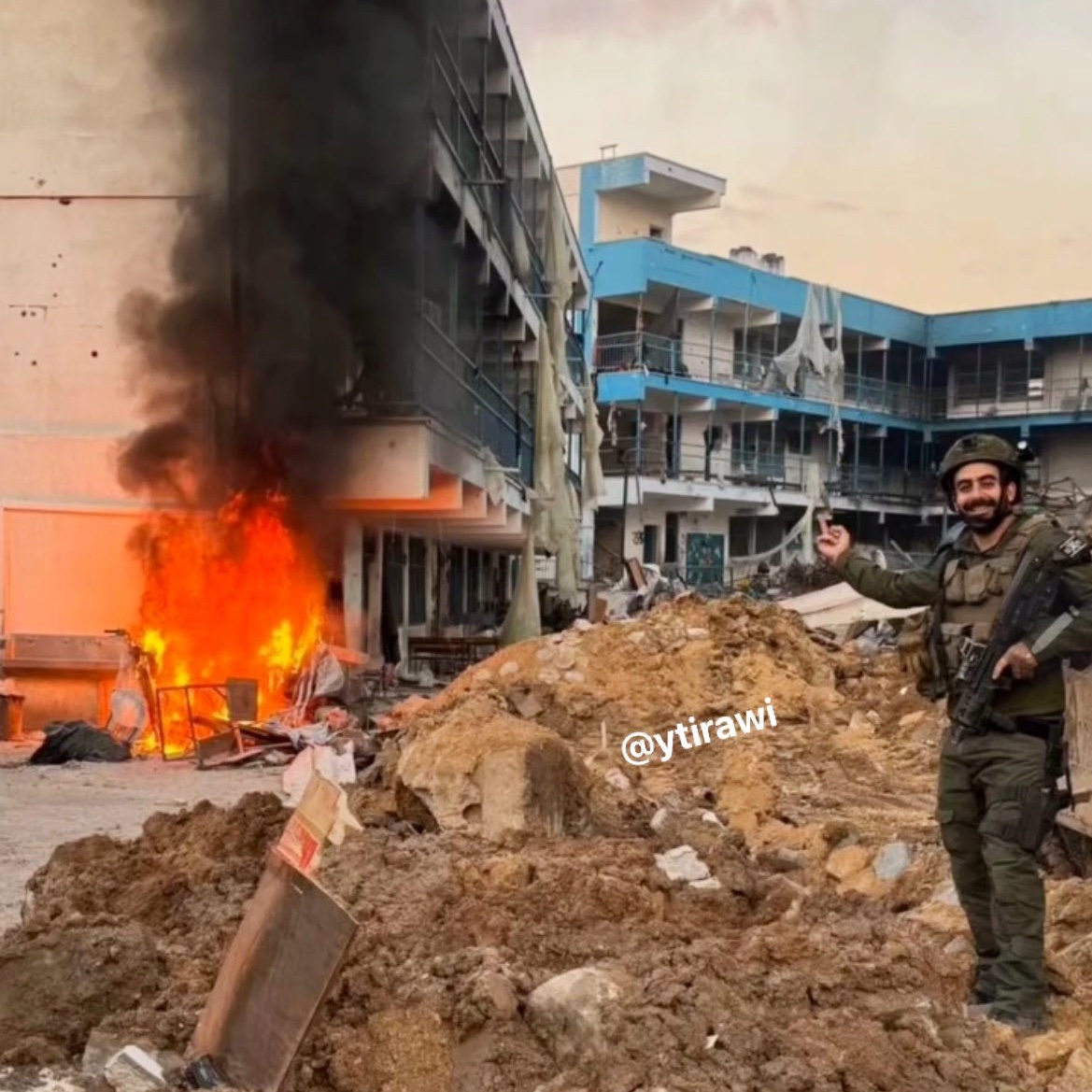 🚨🇮🇱 ZIONIST soldier poses for a photo as he BURNS DOWN a United Nations SCHOOL in Gaza!