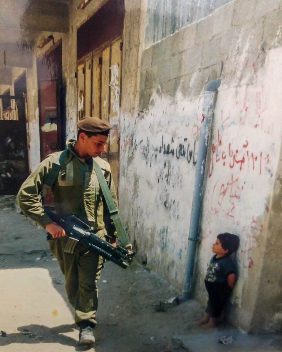 Un soldado sionista apunta con su fusil a un niño palestino de 4 años que esta en la calle Mansoura, en el barrio de Al-Shujaiya, al este de la ciudad de Gaza. Esta foto es de 1993, entonces Hamás no gobernaba Gaza, pero los sionistas dicen que todo empezó el 7 de octubre.