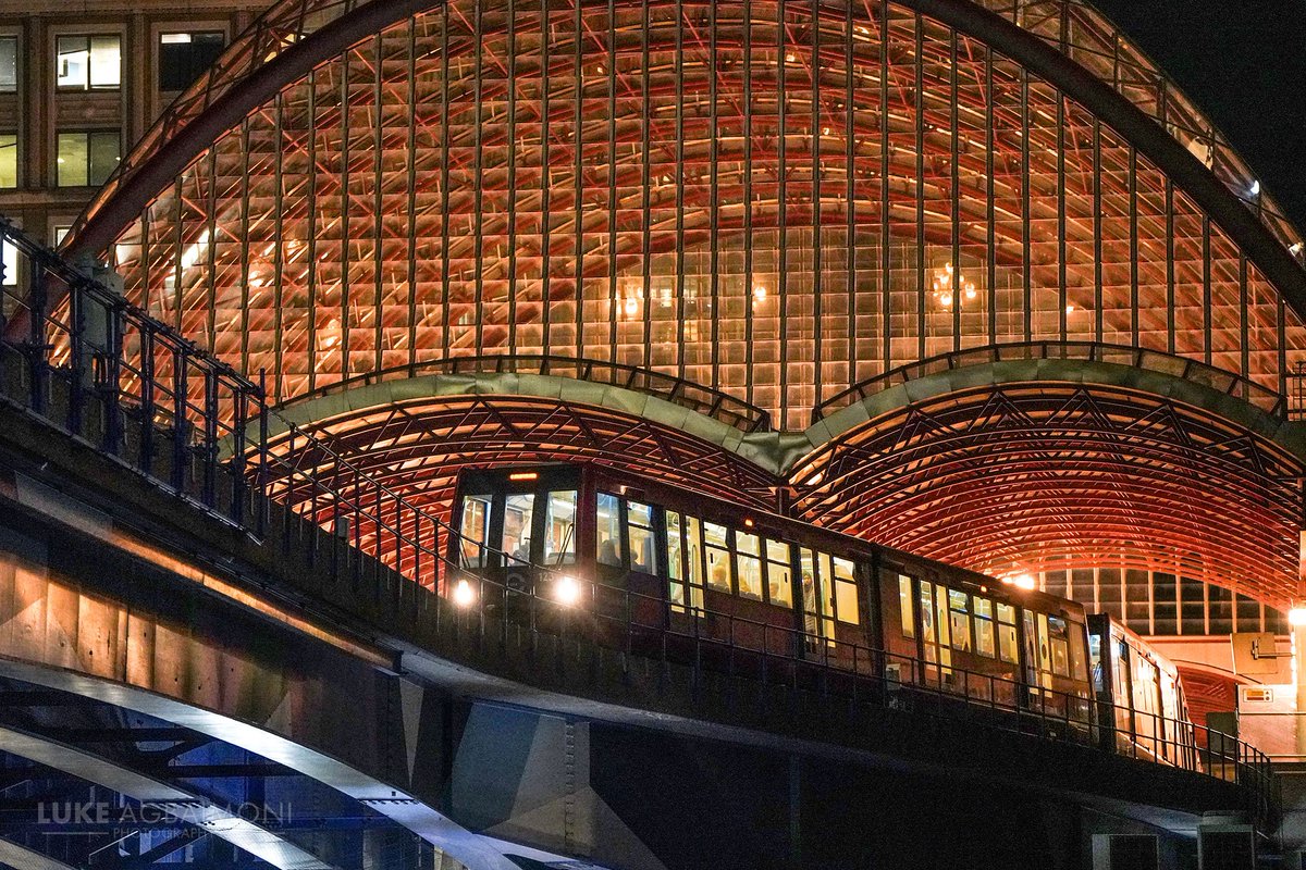 Leaving Canary Wharf Night photography capturing a Docklands Light Railway train heading towards Heron Quays station. I'm a big fan of the Canary Wharf DLR building in the background & I love the lights shining through it's curved canopy structure. #wexmondays #fsprintmonday