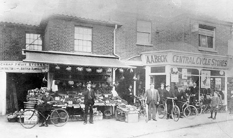 Photograph of Edward Troller's Cheap Fruit Stores and A.A. Beck's Central Cycle Stores in the Narrows, #Cromer around 1910. Edward Troller stands outside his store.