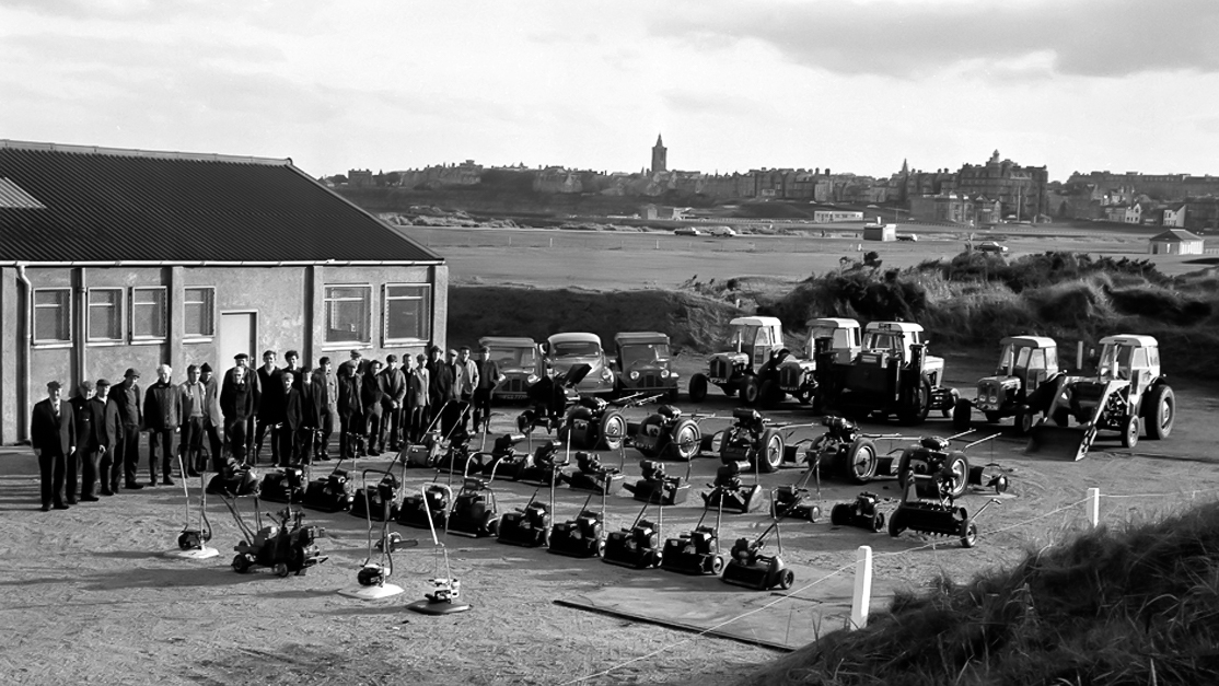 Scenes from St Andrews Past… The Greenkeeping Team showing off their equipment at the Jubilee Shed in 1958. Whilst technology has changed, the silhouette of the Auld Grey Toun remains unmistakeable. #StAndrews #theHomeofGolf #Greenkeeping