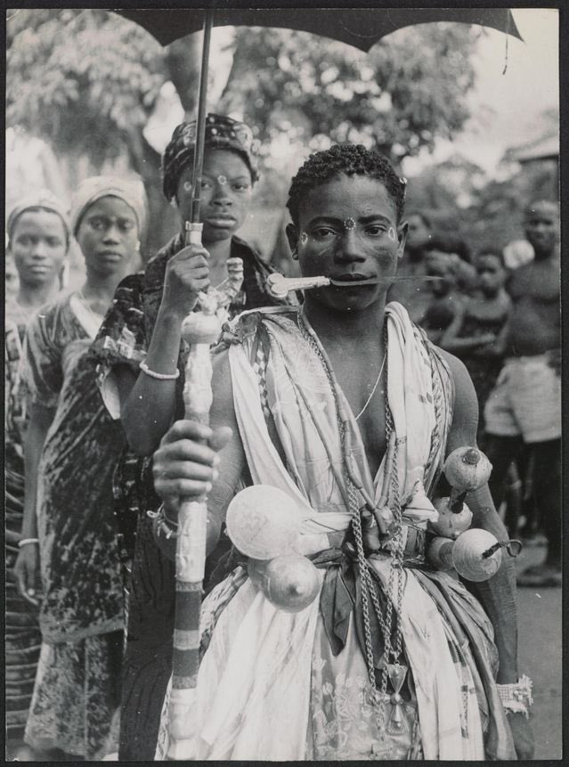 c.1935 - Man adorned with extensive gold jewellery and swords at a festival in present day Côte d'Ivoire.

Photographed by Vernon McKay