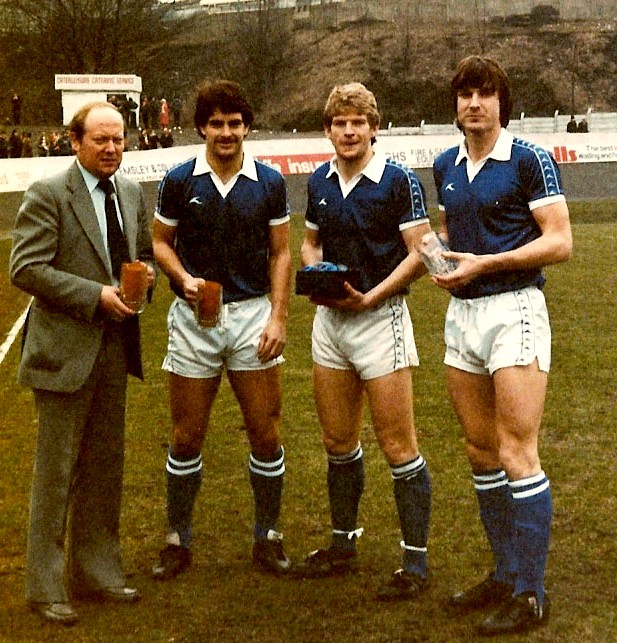 Halifax Town players Dave Evans, Steve Spooner & Steve Ward receive (I think) Man of the Match awards from director John Crowther, 1981/82. Good shot of the snack bar in the away end. 📷Keith Middleton.