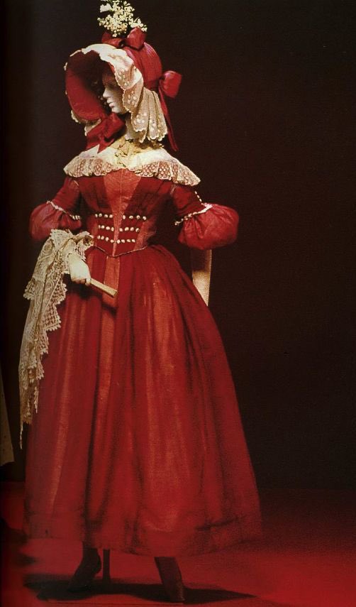 Such a splendid red, gorgeous shades punctuated with white decorative buttons. The sleeves are especially ornate as you would expect of a mid #1830s gown. From elaborate bonnet to trailing lace wrap, it exudes warmth and curves #thekyotocostumeinstitute