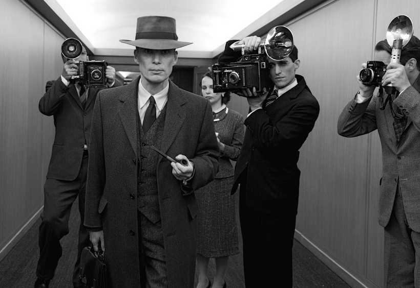 Cillian Murphy as Oppenheimer walks down a hall on the Alhambra, California, set where the 1954 security clearance hearing scenes were filmed.