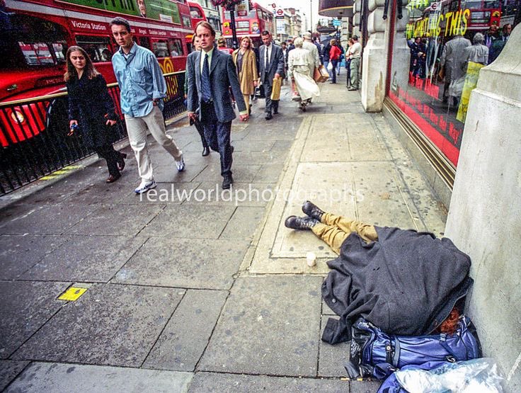 A homeless man is passed out in central London, England as people pass by. Gary Moore photo. Real World Photographs. #london #malmo  #sweden #england #homeless #poverty #unitedkingdom #photojournalism #streetphotography #realworldphotographs #photography #garymoorephotography