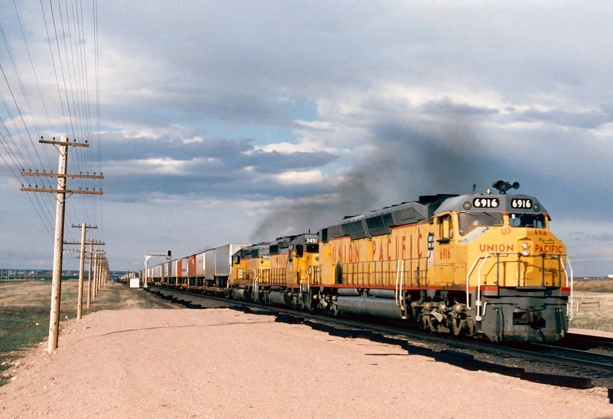 Union Pacific DDA40X 'Centennial' #6916 (boasting 6,600 hp) leads a westbound freight train out of Cheyenne, Wyoming during a late summer's day in 1985. These powerful diesels actually proved quite successful for UP, logging millions of miles in service. A handful were even