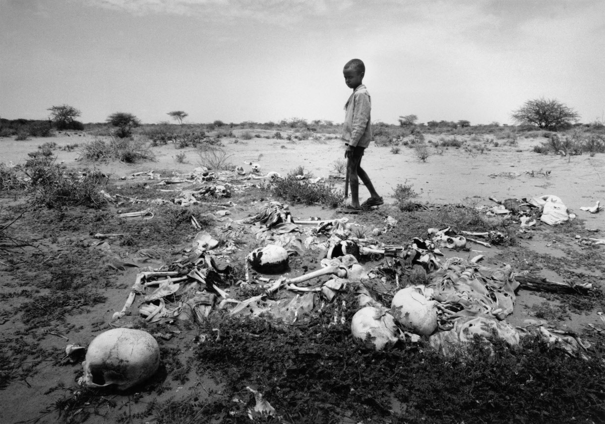 An Isaaq boy stands next to the abandoned remains of his young clansmen, massacred by Somalia government forces. Burao, 1989.