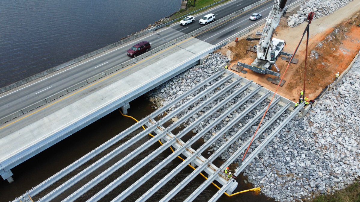 Santa Rosa Co - Work continues on the US 90 bridge over Simpson River. Workers are placing a final concrete beam for a segment of the new eastbound bridge. Beneath them, tons of rock are used to reinforce the foundation of the bridge approach. Estimated completion in mid-2025