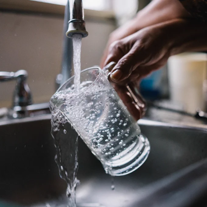 Closeup of a glass of water being filled at a sink.