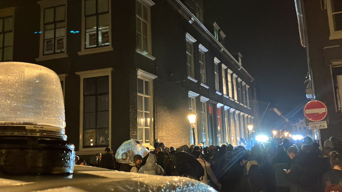 Agenten hebben een ruit geforceerd aan achterzijde gebouw om binnen te komen. Buiten laait het gezang weer op. Focus ligt op zijkant van het gebouw, de Boothstraat.