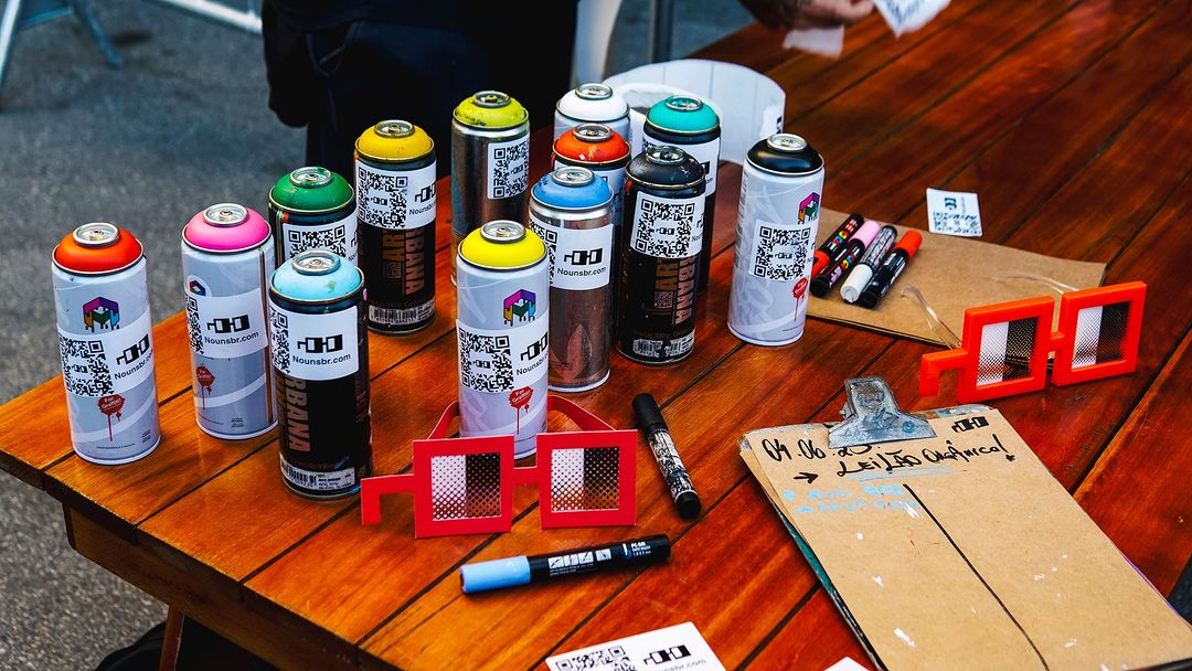Confira a parceria entre Josué Gonçalves e Nouns br no #NFTBrasil23! 🎨 Josué coloriu a entrada da Bienal de SP com grafite, representando a Nouns, que emite NFTs diários que dão voz na Nouns DAO. #NFTs #ArteDigital #Grafite