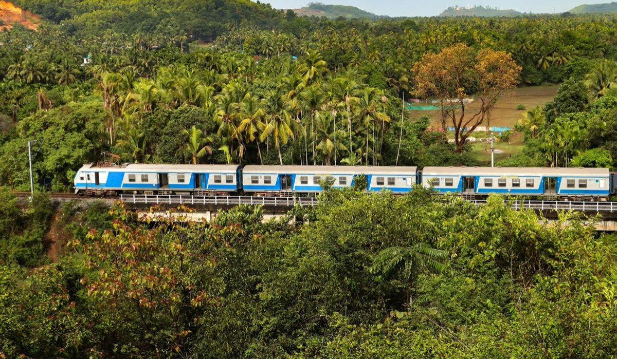 Progressing along its track near Shiroor Railway Station, Karnataka, a MEMU train cleaves through the monotony of a verdant emerald expanse.