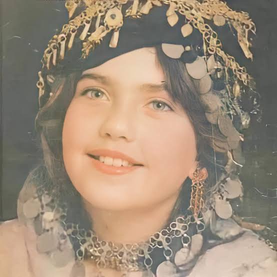 Kurdish girl wearing traditional head decoration and jewelry, c. 1970s.