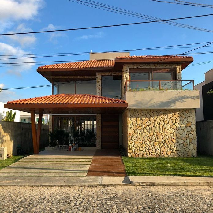 Fachada revestida com pedra e porta de madeira.

Opinem