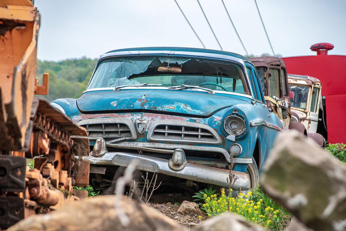An old vintage car sits in a display of scrapped vehicles in a roadside scrapyard in rural Pennsylvania.