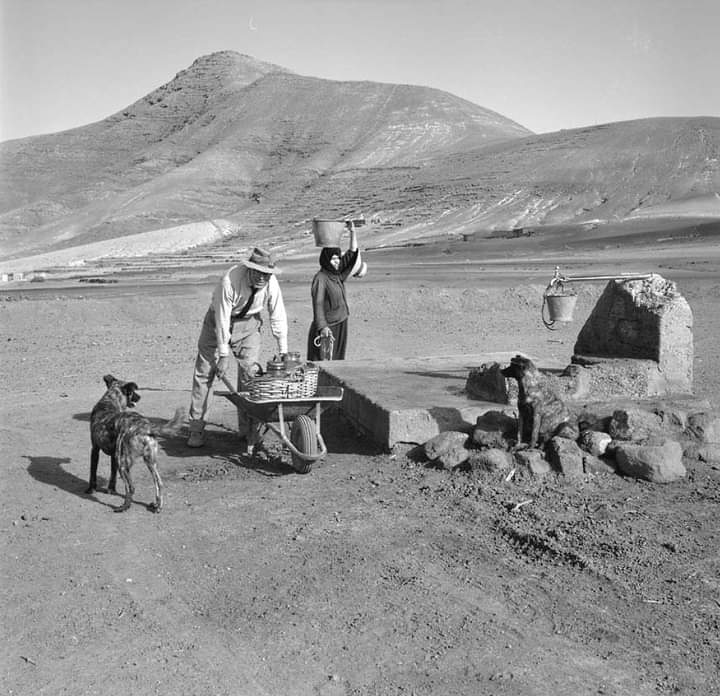 Buen día 🌤️ Muy #FelizViernes #BuenFinde... ¡La lucha por el agua en #Canarias! 𝗨𝗻 𝗔𝗻𝘁𝗲𝘀! Acarreando agua en el chorro. La Matilla, Llano de La Mareta. #Fuerteventura Año1964 📷➡Nicolás Muller (1913-2000 †) 📷#AntiguaTenerife