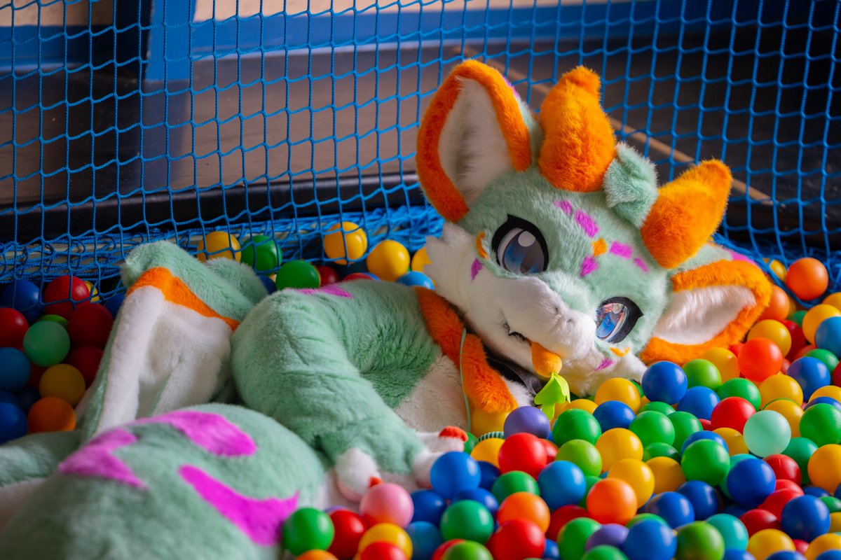 Green dragon in a sea of colours 📷: @LennyaaFluff #FursuitFriday #Fursuit #RyukiCarrotDragon