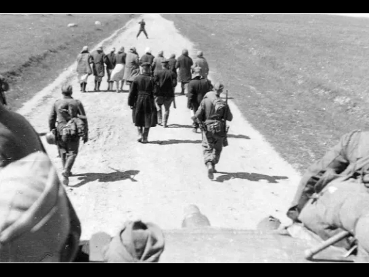 Немецкие солдаты гонят группу советских женщин по дороге для разминирования  от возможных противопехотных мин. Трое гражданских с винтовками - полицаи. Снимок сделан с немецкого танка. Белоруссия. 1942 год.