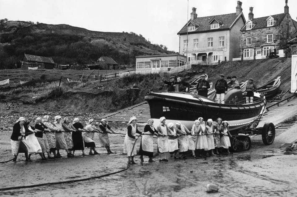 A photograph of the Women of Runswick Bay in Yorkshire, pulling together on the rope to help launch the lifeboat. Taken on the 13th March in 1940.