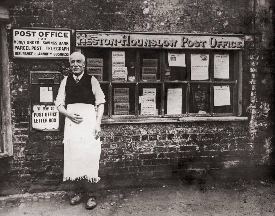 A postmaster stands outside his post office in Heston, Middlesex, taken in the 1920s