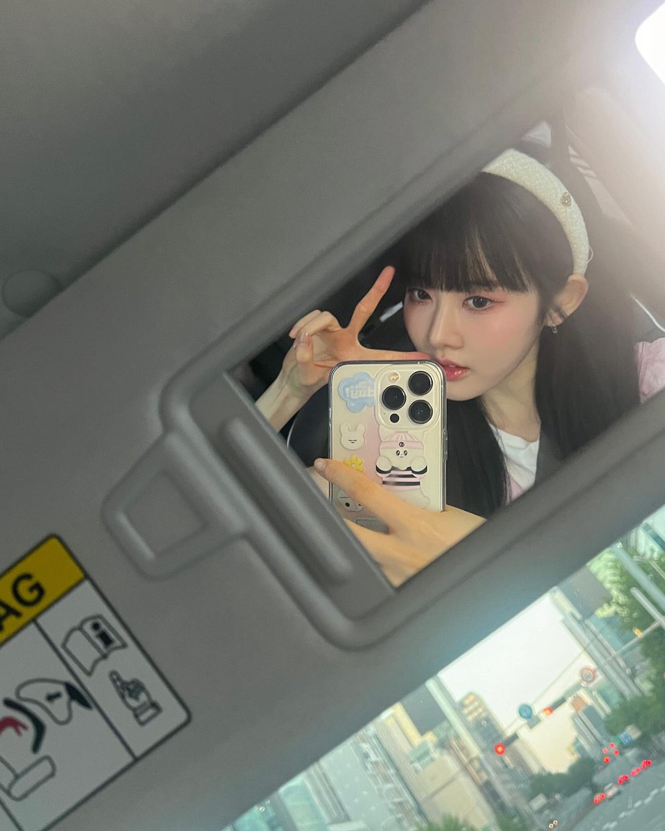 In a realm where delicate blossoms adorn the morning light, she sits with an ethereal grace, her visage framed by a halo of raven hair and crowned in the softest hue of rose.