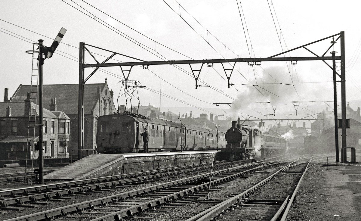 Trains waiting to leave from the Derbyshire terminus; an electric set, later BR class 506, is working the shuttle to Hadfield with J11 0.6.0 64306 brewing up to set off to Woodley.  30 October 1956.

Photo by Kevin Lane
flic.kr/p/K8LviQ
