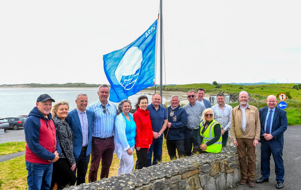 Cathaoirleach of Mayo County Council, Cllr Michael Loftus raising the Blue Flag at Ross Beach, Killala alongside fellow councillors Cllr Jarlath Munnelly, Cllr Mark Duffy, Mayo County Council staff and local residents.