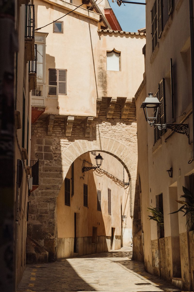 De construcción gótica, el Arco de la Almudaina se levanta en el mismo lugar que ocupaba una de las puertas de la ciudad romana y es la entrada a una de las calles más intensas del casco antiguo, ya que en la calle Almudaina se ecuentran dos de los patios más belllos de Palma😍