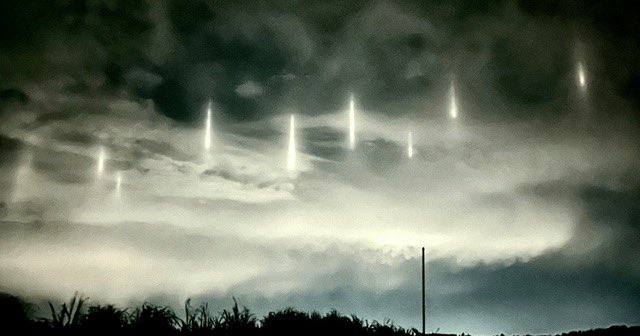 9 pillars of light appear in night sky above coastal Japanese town.