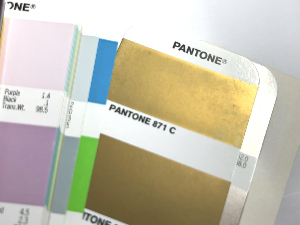 みんなネットやスマホで色確認して「ドドメ色かよw」「CMYKで指定して」「RGBで(略)」「HEX(略)」みたいなリプがついてるけど、PANTONE 871 Cは金色です。DICなら620あたりか。
こんな行き違いがあるとまずいので変態おじとデザイナー女は色合わせのためにリアルする必要があります。