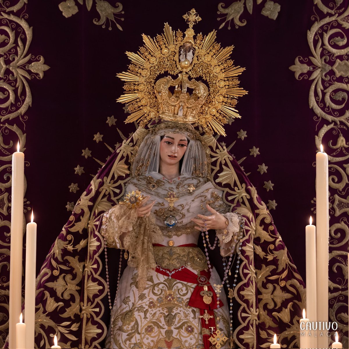 CULTO - Para los cultos por el #DíadelaTrinidad, María Santísima de la Trinidad Coronada luce saya de tisú rosa bordada en oro, manto de coronación de terciopelo cardenal bordado en oro, la corona de coronación y rostrillo de tablas realizado con encaje de hojilla. #CofradíasMLG.