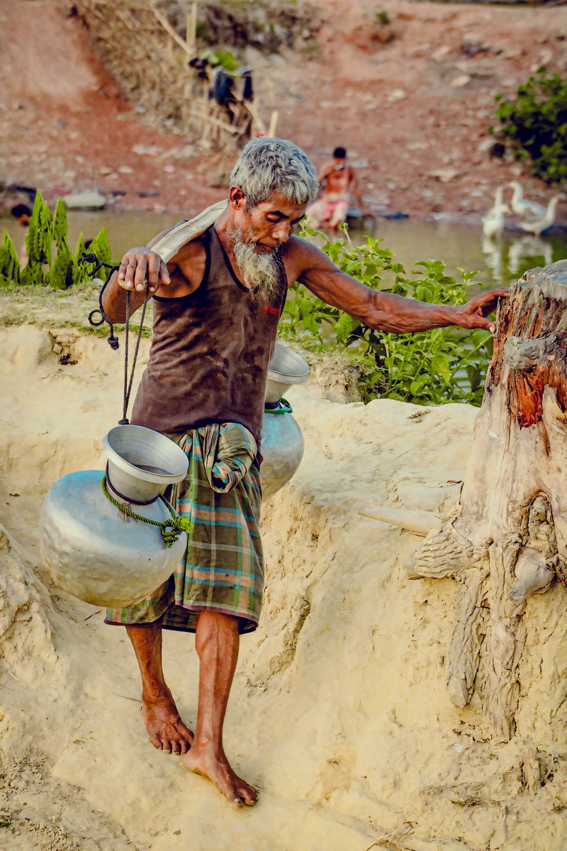 Nur Mohamed is a elderly man. He is carrying water with a bar (Bok). Water problems occur in various areas during summer. Many are suffering from diarrhea and cholera due to not being able to drink safe water.

 #waterproblem  #documentaryphotography #waterforall #dailyneeds
