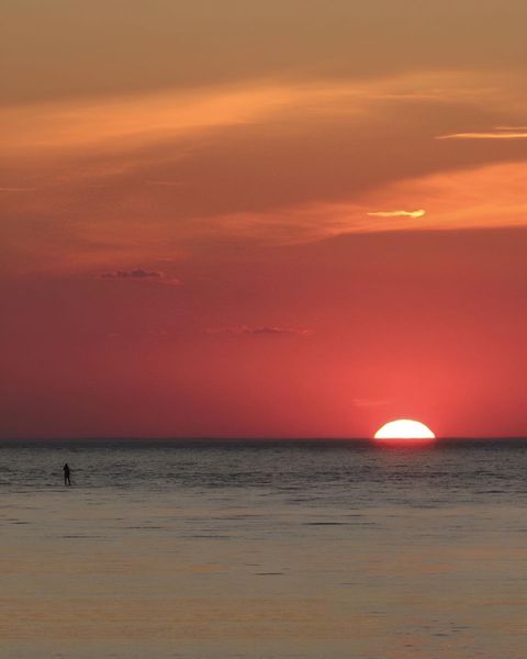 A lone paddle-boarder witnesses a summer sunset on Cape Cod