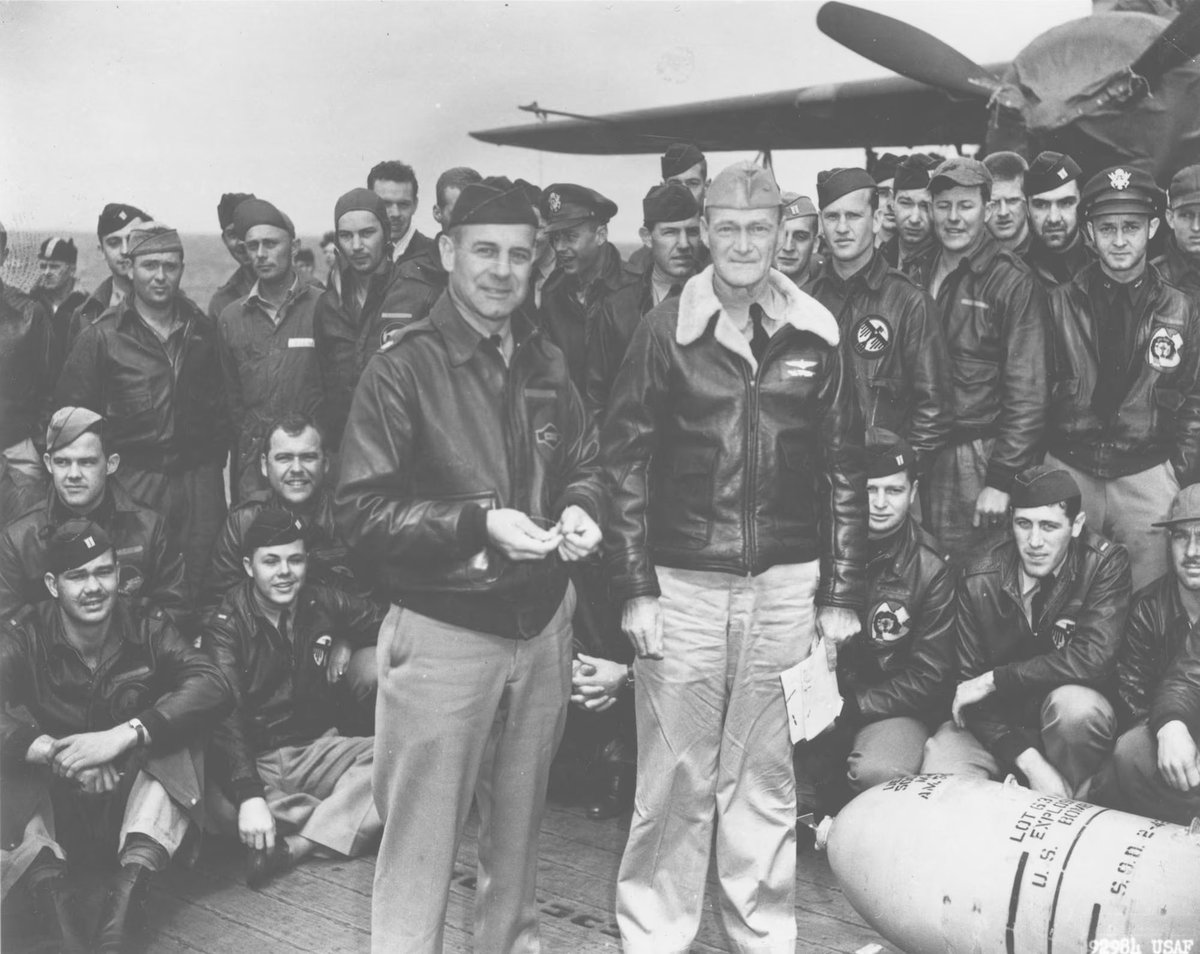 April 1942.. Lieutenant Colonel James H. Doolittle & Captain Marc A. Mitschler (Commanding Officer) of the US Navy Aircraft Carrier USS Hornet (CV-8).. Pose with a 500lb. Bomb & USAAF Aircrew during ceremonies on Hornets Flight deck while the raid task force was enroute to the
