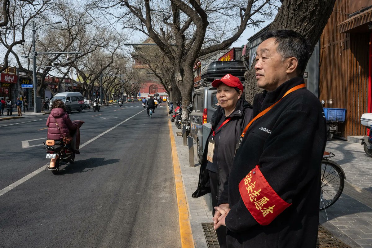 'Volunteers from a neighborhood committee keeping watch on a Beijing street.' They don't regard this as a chore; they enjoy it. The aggressively conventional-minded are always there, in every country. All they need is an excuse to go after the rest of us.