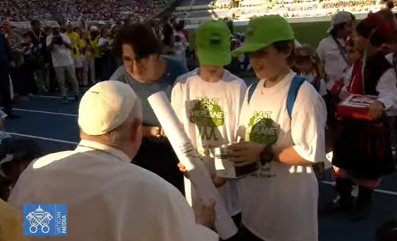 Children bring Pope Francis gifts, including 2 baskets filled with letters, 5,000+ drawings. Riad from Syria gives pope a photo he took in 2016 when Pope Francis let him fly to Italy on the papal plane from a refugee camp in Lesbos, Greece.