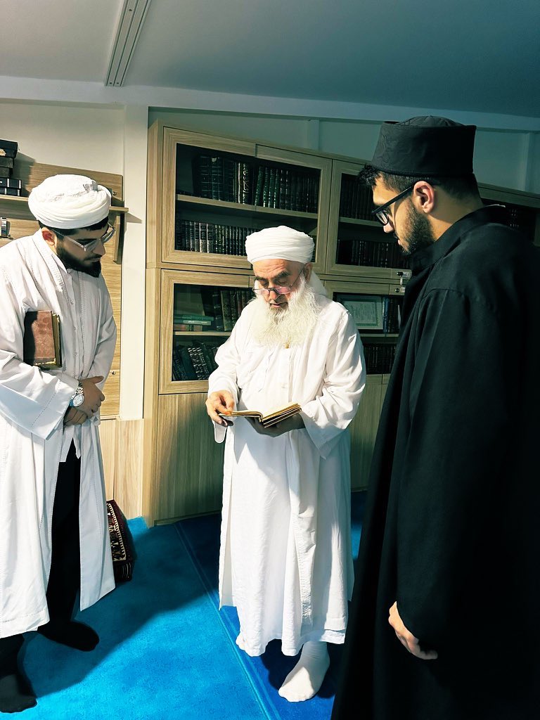 Hüseyin Avni Hocamız kütüphanesinde misafirlerine tarihî kitap tanıtırken..