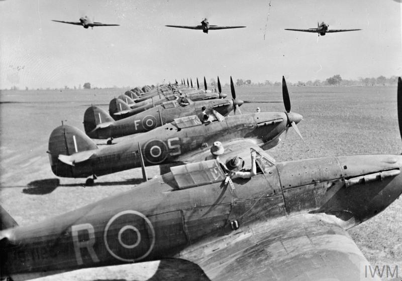 A section of Hawker Hurricanes fly over the Hurricane Mark IIBs and IICs of No. 67 Squadron RAF, lined up at Chittagong, India, during the Second World War. IWM (CI 178)