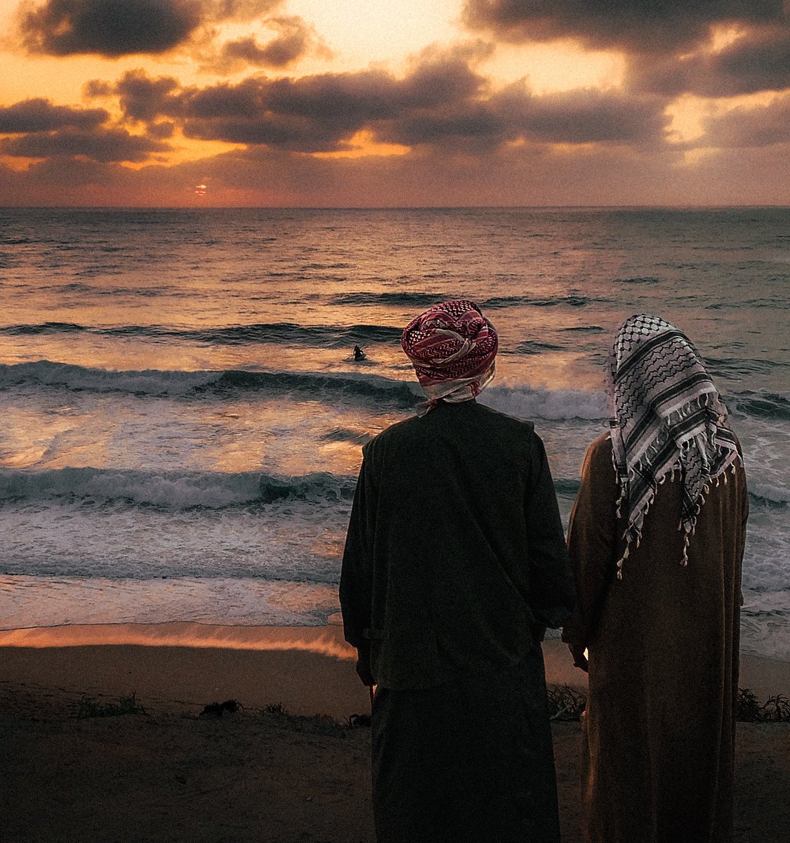 Two elderly palestinian friends, wearing their kufiyyehs watching the sunset at the beach of Deir al Balah.